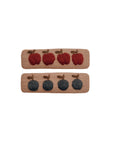 Two linen hair clips embroidered with fruit: one with navy blue berries and the other with red apples, displayed flat on a light neutral background.